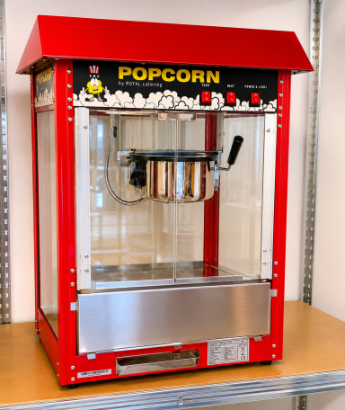 Rote Popcornmaschine mit Glasfront und Edelstahlablage, bereit für die Zubereitung.